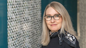 Taru Feldt vid Jyväskylä universitet. Taru Feldt tittar in i kameran över axeln. Hon ler något.