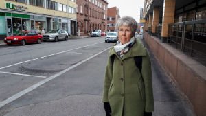 Marita Bagge skulle gärna parkera bilen på Krämaretorget om parkeringen var gratis. En kvinna står vid sidan om en väg inne i en stad.