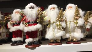Givandets glädje. Också julgubben ska ha dricks? Vita, röda och svarta julgubbar på dekorationshyllan på varuhus i New York