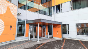 I Nickby samsas både de finska och svenska eleverna i åk 7-9. För att minska risken för smittspridning släpps inga utomstående in. Ingången till skolcentret i Nickby. Orange väggar och dörrar i glas.