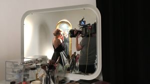 Anu Sinisalo poserar som Marilyn för fotografen Mikko Kilpinen. Anu Sinisalo står i en svart dress framför en spegel.