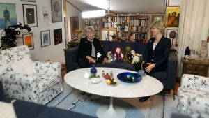 Tänk så fint om vi alla bara kunde komma överens. Lite som Elisabeth och Elisabeth. Elisabeth Rehn och Christoffer Strandberg sitter på en soffa. Christoffer är utklädd till Elisabeth i kavaj, peruk och pärlhalsband.