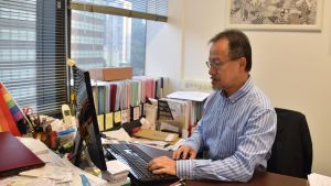 Fernando Cheung har förgäves kämpat för fullskalig demokrati i mer än ett decennium. Nu har han förståelse också för de militanta demonstranterna. Man i blåvitrandig skjorta skriver på bordsdator. I bakgrunden syns mappar innehållande papper.