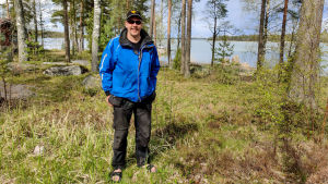 Timo Salmia är optimistisk och tror att bryggprojektet går att genomföras. En man i blå jacka står i en skogsdunge.