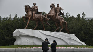 Två män visar sin respekt inför statyer av landsfadern Kim Il Sung och sonen och arvtagaren Kim Jong Il Två män visar sin respekt inför statyer av landsfadern Kim Il Sung och sonen och arvtagaren Kim Jong Il