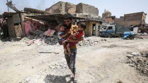 IS-terroristerna har använt civila som människosköldar i Mosul. Man bär på två barn mitt bland ruiner i Mosul.