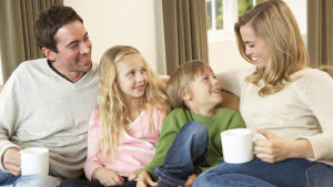 Barn vill ha mer tid med sina föräldrar. Familj med två vuxna och två barn ungås i soffan.
