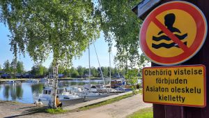 Obehöriga ska hålla sig borta - men hamnen är ändå allmän plats, där alla får röra sig. Simning är ändå förbjuden i hamnområdet. en förbudskylt mot simning fäst på en husvägg, intill en småbåtshamn