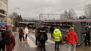 På plats bjöds det även på lite mat och dryck åt dem som kommit för att jobba, som den lokala kiosken hade donerat åt talkoarbetarna. En grupp människor står och lägger upp stängsel vid järnvägen. Ett tåg kör förbi i bakgrunden. Det är mulet.