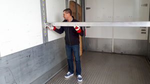 Transportföretagaren Patrick Andersson kör papper, byggmaterial eller styckegods. En man sätter upp en bom inne i ett lastutrymme i en långtradare.