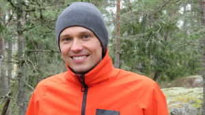 ... Johan Gullmets är en mästare bakom kameran, men också van att stå framför den och reda ut olika begrepp. En man i grå mössa och orangefärgad jacka står i en granskog. Han ser glad ut.