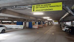 Tydliga skyltar för den som ska till drive-in-coronatestningen. En gul skylt vid infarten till ett parkeringshus informerar om att här finns en driv-in-coronatestning.