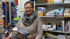 I den gula mappen bakom Eva Lignell finns ungdomarnas obetalda skolböcker, pennor och häften prydligt inskrivna för hand. Det här är ett system många Karisbor känner till. En kvinna står bakom en betjäningsdisk i en bokhandel.