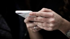 Man kan sända ett sms till ungdomsarbetarna för att komma i kontakt med dem. Ung kvinna håller i mobiltelefon.