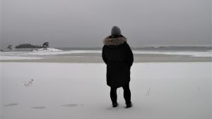 Balans mellan jobb och fritid och livskvalitet samt möjligheten till ett naturnära liv. Det uppskattar Cata Holappa i Hangö. Kvinna tittar ut över snöig strand och hav