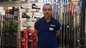 Mertsi Raitanen, butikschef för Intersport vid Hansa och Skanssi. butikschefen mertsi raitanen står framför ett utbud av skidor och skidskor