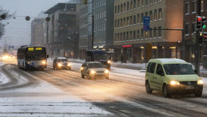 Bilskola L. Holmberg lät sina elever köra i Helsingfors så att de skulle lära sig hur man kör då det finns trafikljus. Autoja mannerheimintiellä lumisateessa aamuhämärässä