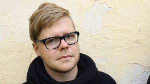 Veikka Lahtinen menar att WWF i de olika länderna räknar på olika sätt. Veikka Lahtinen seisoo keltaisen seinän edessä.