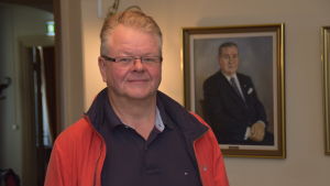 Jan-Mikael Ekholm i stadsstyrelsens gamla mötesrum. På väggen en tavla som föreställer en av Ekenäs stads tidigare fullmäktigeordförande, Tor Willberg. En man i ett stadshus, stadsutvecklingssektionens ordförande.