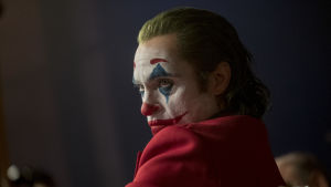 Närbild på Joker (Joaquin Phoenix) iklädd clownmask och röd kostym.