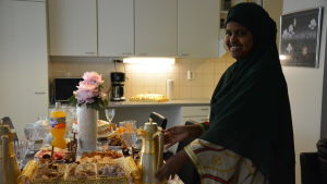 Saedo Weheliye dukar fram somaliskt kaffe till den söta festmåltiden. På bordet finns olika slags söta bakverk. Efter fastan vill man äta något lätt, säger hon. Kvinna dukar fram te och läckerheter.