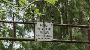Porttimainen rakennelma, jossa kiinnitettynä kyltti. Kyltissä lukee "Mehu Villa Seve Sinistö, Humaljärvi, Vecklax, Alue 12, Palsta 3".