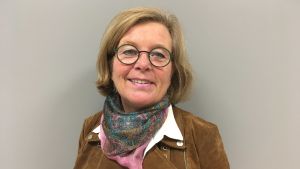 Kauppila säger att hon själv också har svårt att använda sitt modersmål, svenska, på sjukhuset, då hon också kan finska. wiveka kauppla leende mot kameran iklädd brun jacka mot en grå bakgrund.