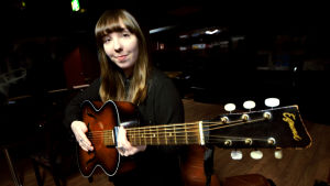 Anna-Stina Jungerstam arbetar periodvis med musik på heltid. Anna-Stina Jungerstam håller en gammaldags akustisk gitarr.