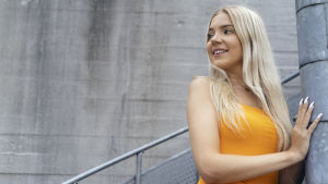 Molly trodde att hon skulle vara noggrant medveten om kamerorna under tv-inspelningarna. Men hon säger att hon glömde det så gott som genast. Molly Nybondas står i trappan och ser mot vänster. Hon är klädd i en grann orange klänning och ser glad ut.