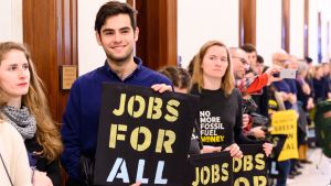 Demonstranter från Sunrise Movement protesterar utanför republikanska senatledaren Mitch McConnels kontor i Washington. Aktivister håller upp skyltar med orden "Jobs For All" - Jobb för alla.