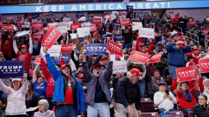 Trumpanhängare i Hershey i delstaten Pennsylvania. Kampanjevenemangen har alltsedan Trump inledde sin presidentvalskampanj år 2015 varit en central del av hans politiska profil. En bild på massa människor som ropar och håller i plakat där det står "Trump Pence". Plakaten är röda, blåa och vita.