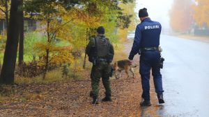Polisen letade efter kvinnan med hjälp av polishundar och drönare. Två poliser står med ryggen vänd mot en kamera, en polishund går framför poliserna.