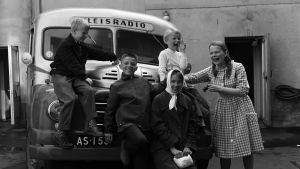 Lasten Radio lähdössä ohjelmakiertueelle vuonna 1960. Pakettiauto starttasi Fabbarilta. Iloista radioporukkaa luotsaa ruutumekkoinen ohjaaja Raiku Kemppi, jonka vieressä nauruaan pitelee vaalea-asuinen seitsenvuotias Tiina. Lasten Radion väki lähdössä ohjelmakiertueelle vuonna 1960.
