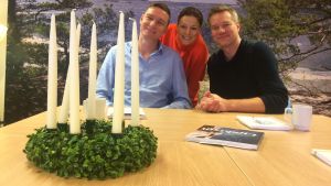 Steffen Ørsted, Mia Hafrén och Mårten Svartström är årets luciajury. Luciajuryn bestående av Steffen Orsted, Mia Hafrén och Mårten Svartström sitter i ändan på ett bord med en luciakrona på bordet.