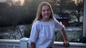 Frida Sjöblom. Frida lutar med ena handen mot ett staket