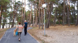 Tiina ja Kimmo Linkama Võsun rantatiellä Latte-koiran kanssa Nainen ja mies kävelevät koiran kanssa mäntymetsän läpi rantatiellä meren äärellä