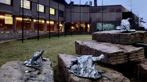 Hanaholmen möter med kultur vid ingången. Kaarina Kaikkonens metallstatyer: ytterrockar på stenblock utanför Hanaholmen