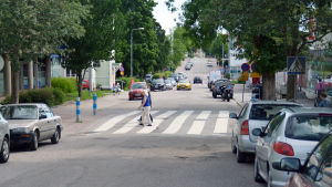 Staten: Raseborg borde utveckla sina centrumområden, inte breda ut sig i glesbygden. På övre bilden Ekenäs centrum och på nedre Karis centrum. Några personer går över ett övergångsställe vid en väg där många bilar har parkerat.