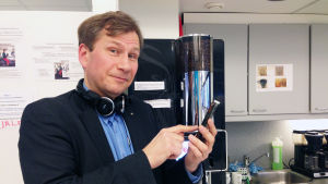 Kommunikationsexperten Reidar Wasenius svarar Reidar Wasenius med mobiltelefon vid kaffeautomat