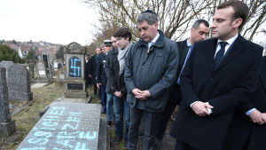 Macron under besöket på gravgården. En bild på president Macron vid en gravgård i Frankrike som har vandaliserats.