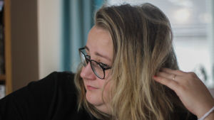 Ellen Strömberg, en vit kvinna med blont hår och svarta glasögon ser åt sidan.