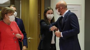 Statsminister Sanna Marin representerade Finland under helgens toppmöte. Sanna Marin armbågshälsar med Charles Michel. Tysklands förbundskansler Angela Merkel tittar på från sidan. Alla är iklädda munskydd.