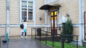 På musikinstitutet vid Raseborgs Kulturinstitut är det munskydd som gäller. kvinna går in i ett gult hus