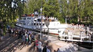Insjöfartyget M/S Suometar i kanalsluss, flera människor står och tittar på.