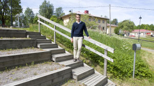 Henrik har fått jobba lite extra för att bygga upp ett förtroende. En man iklädd en ljusblå skjorta och en mörkblå tröja. Han är utomhus och han lutar sig mot ett trappräcke. I bakgrunden skymtar en skola och en lekplats.