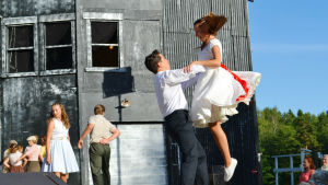 Birk Lerviks och Vilma Eklöv spelar huvudrollerna i West side story på Rasebrogs sommarteater. Pjäsen ges ännu ett par gånger. En man lyfter upp en kvinna på en scen i en dans. mannen bär svarta byxor och en skjorta och kvinnan har en vit klänning med rött skärp. De tittar varandra i ögonen. I bakgrunden syns ett högt mörkt hus.