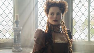 Stirrar den stundande striden stint i ögonen. Margot Robbie spelar en stram drottning Elisabet. MArgot Robbie poserar vid ett fönster i rollen som Elisabeth I.