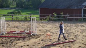 Ridbanan på stallet Westgård. Westman drömmer om att i framtiden också bygga en manege. Ryttaren Patricia Westman flyttar på hopphinder på sin ridplan i Pojo.