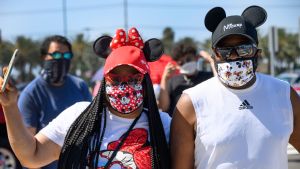 Florida i USA har drabbats mycket hårt av coronaviruset, men trots det väljer Disney att öppna upp sin temapark i delstaten. En kvinna och en man i ansiktsskydd poserar för kameran. Kvinnan bär Mickey Mouse-öron och håller upp sin telefon med ena handen. Mannen har också på sig Mickey Mouse-öron