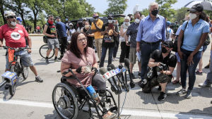 Krigsveteranen Duckworth förlorade sina ben i Irakkriget. Tammy Duckworth sitter i rullstol mitt i en folkhop och håller tal.